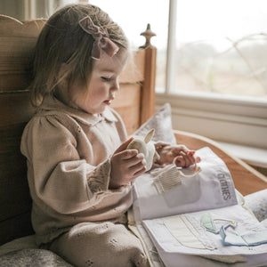 Goodnight Gooseling Activity Book. Girl sitting in bed playing with activity book.