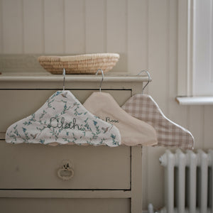 Children's Hanger in Beige Gingham, Ivory and Secret Garden hanging off top of dresser