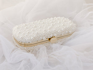 Bella Rosa Collection's True Love Bella Clutch Petite pearl-embellished clutch purse on a tulle fabric background.