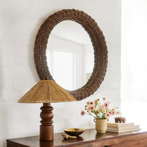 round mirror with table lamp and flowers