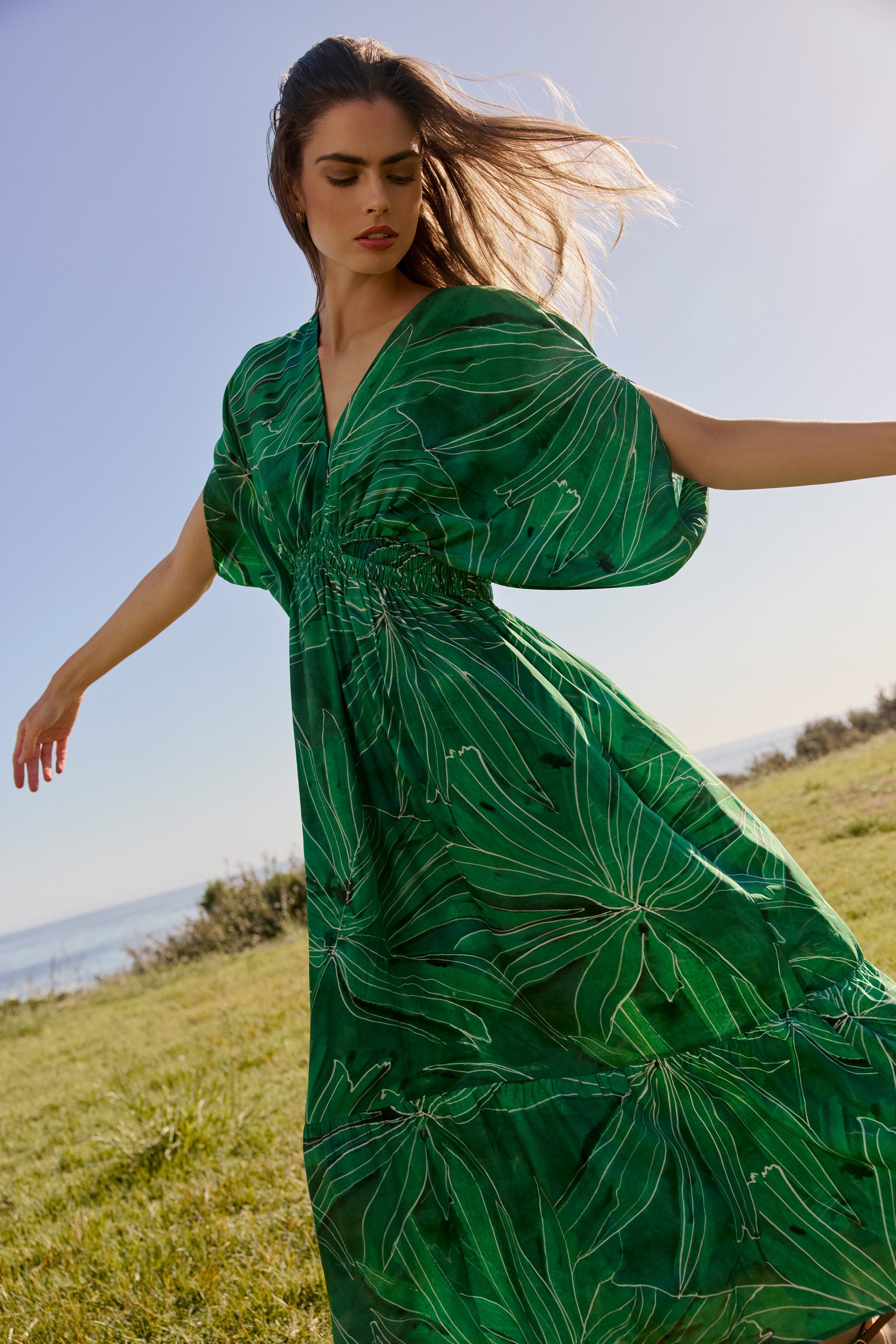 Flowy green dress with oversized leaf pattern and structured waistline