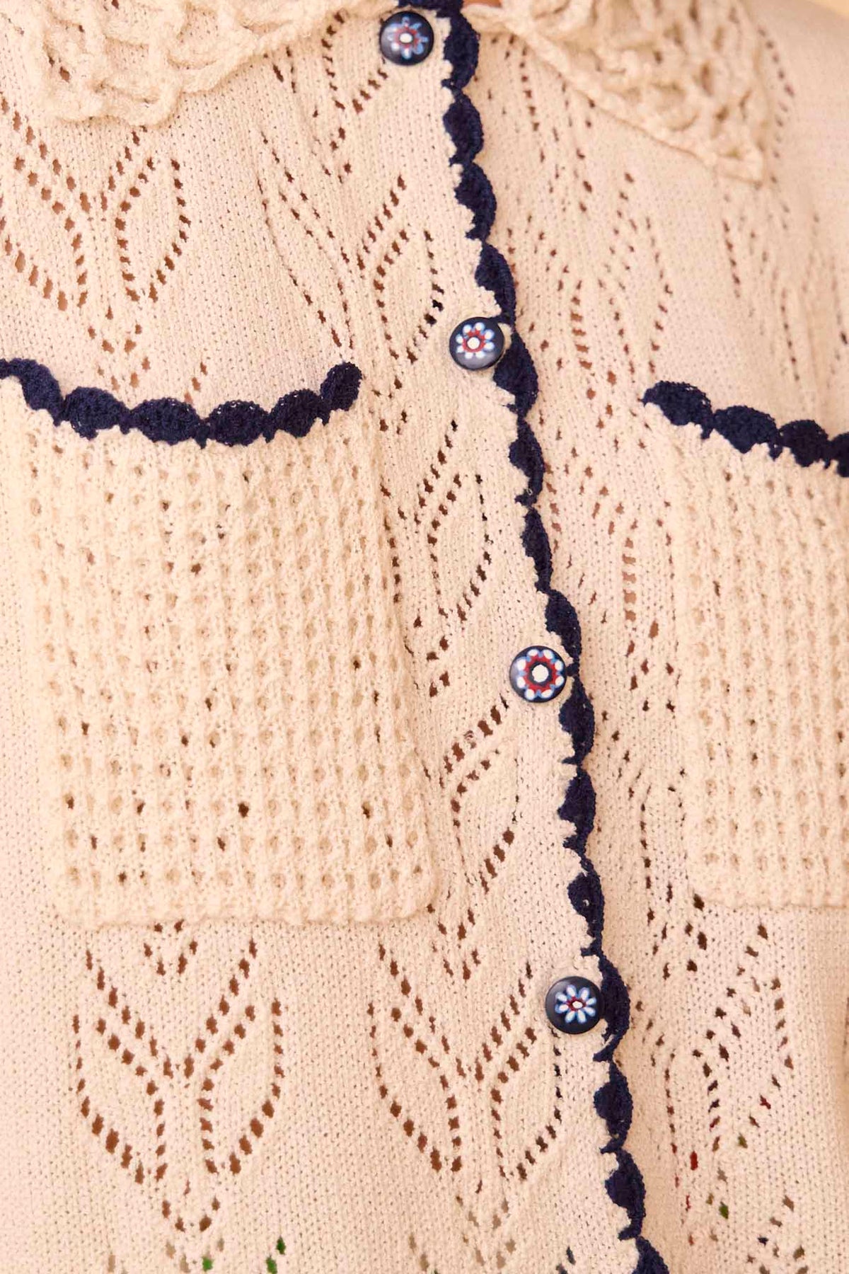 The Ophelia Sweater has short sleeves, novelty painted flower buttons, and scalloped edging.