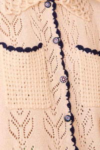 The Ophelia Sweater has short sleeves, novelty painted flower buttons, and scalloped edging.