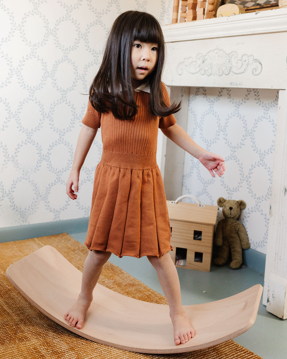 Girl balancing on the wooden rocker balance board