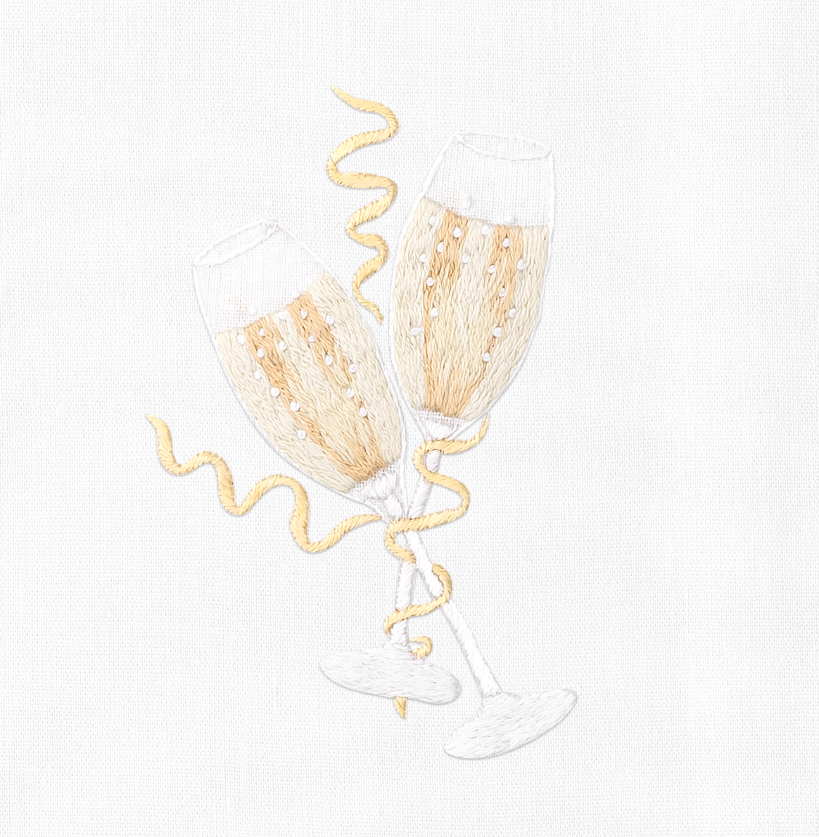 A close up detailed image of the embroidery - Two filled champagne glasses toasting with gold bands wrapped around them.