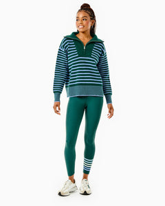 Model is wearing the Griffin Quarter Zip in Ivy/ Violet Stripe with the Everyday Legging in Ivy with violet stripes.