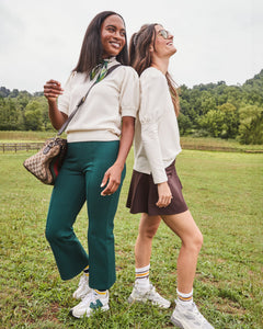 Model is wearing the Locust Active Sweater in Cream with the University Flare Pants in Chocolate