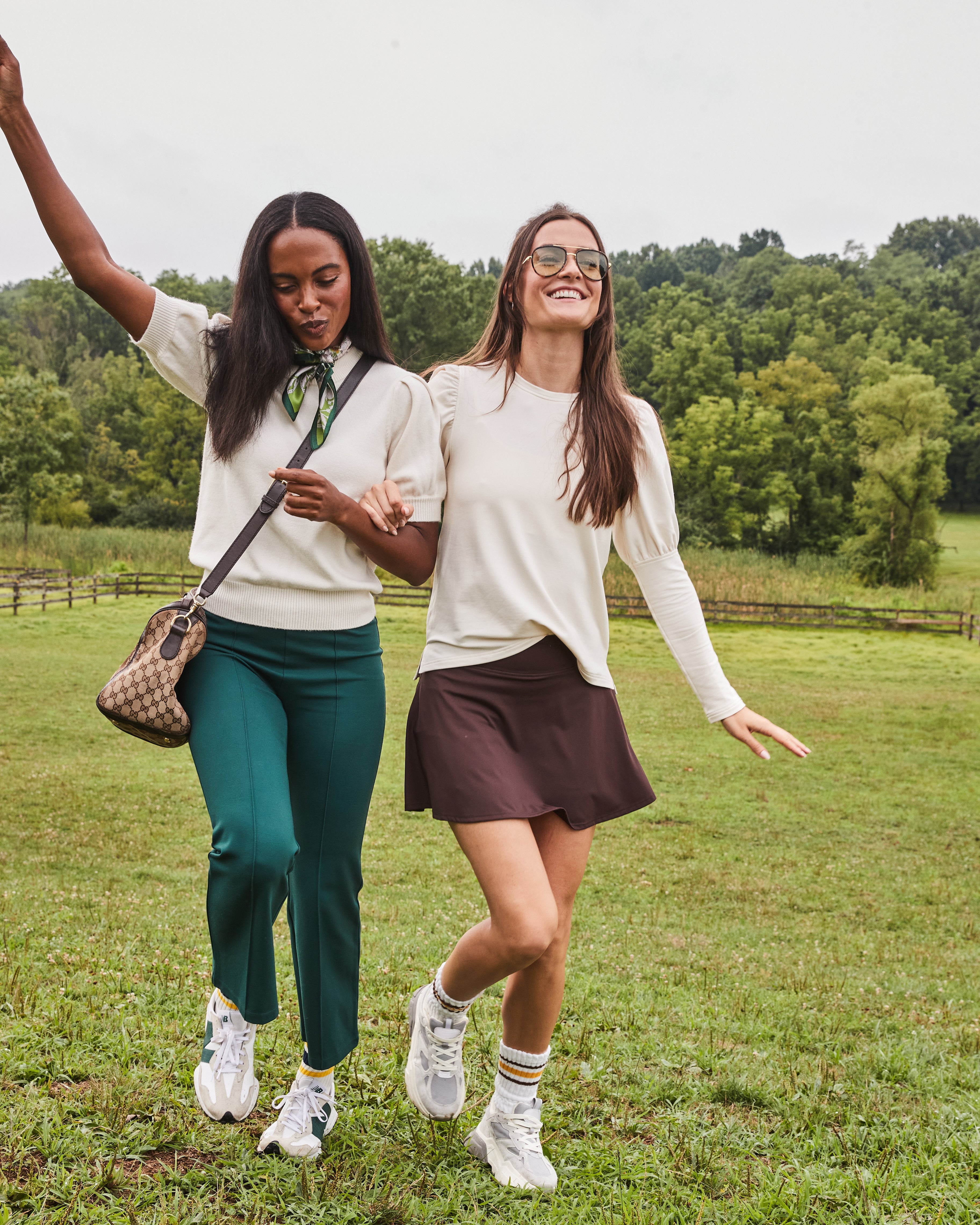 Model right is wearing the Webster Top in Cream with the Flounce Skort in Chocolate. Model left is wearing the Locust Active Sweater in Cream with the Waverly Pants in Ivy.