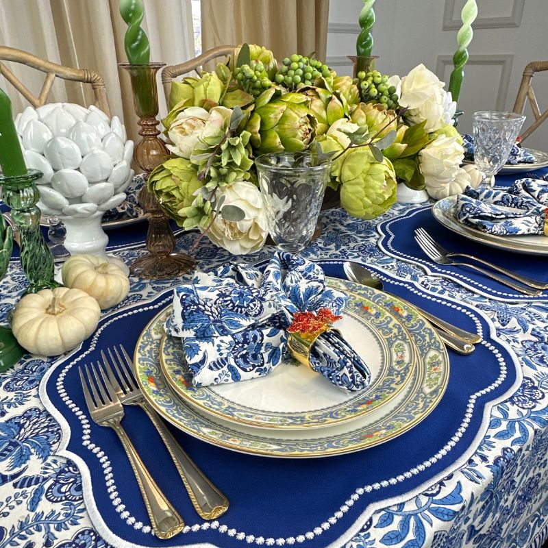 Royal blue placemat with with white embroidery, blue floral table cloth and napkins and leaf napkin rings