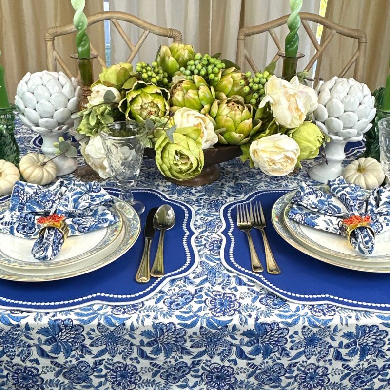 Royal blue placemat with with white embroidery, blue floral table cloth and napkins and leaf napkin rings